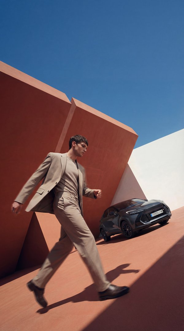 AI photoshoot: man in beige suit with Toyota C-HR against terracotta architecture