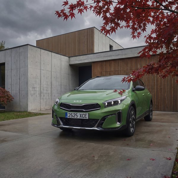 AI product photography: green Kia XCeed at modern home with red maple tree