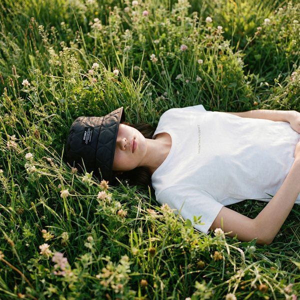 AI photoshoot: woman in Ecoalf quilted cap lying in wildflower meadow