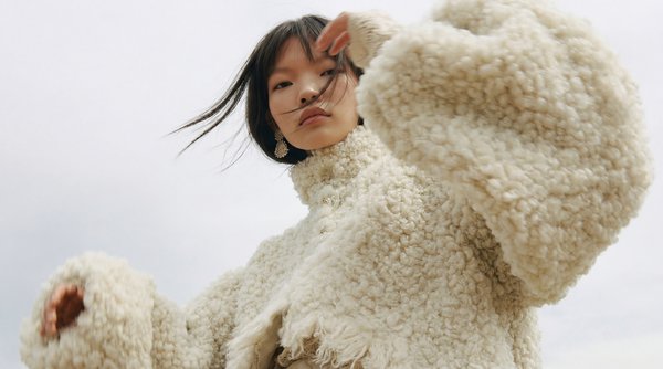 Fashion model in textured cream fleece jacket demonstrating AI on-model product photography